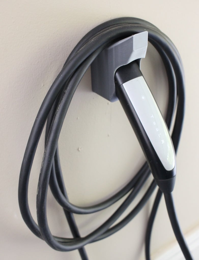 Nástěnný držák nabíječky Tesla s háčkem na kabel